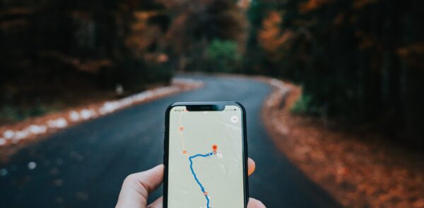 Picture of a person's hand holding a mobile phone while looking for a route in a transport application
